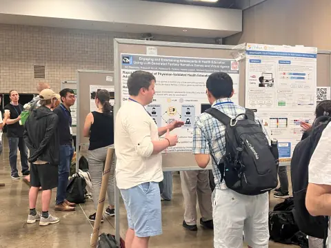 Presenter explaining a poster on LLM-generated fantasy narrative games to a visitor