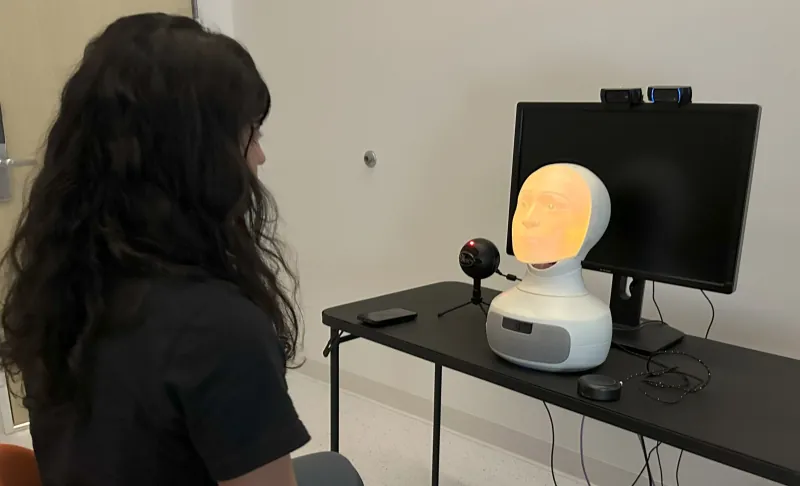 Person facing a Furhat social robot with a back-projected face
